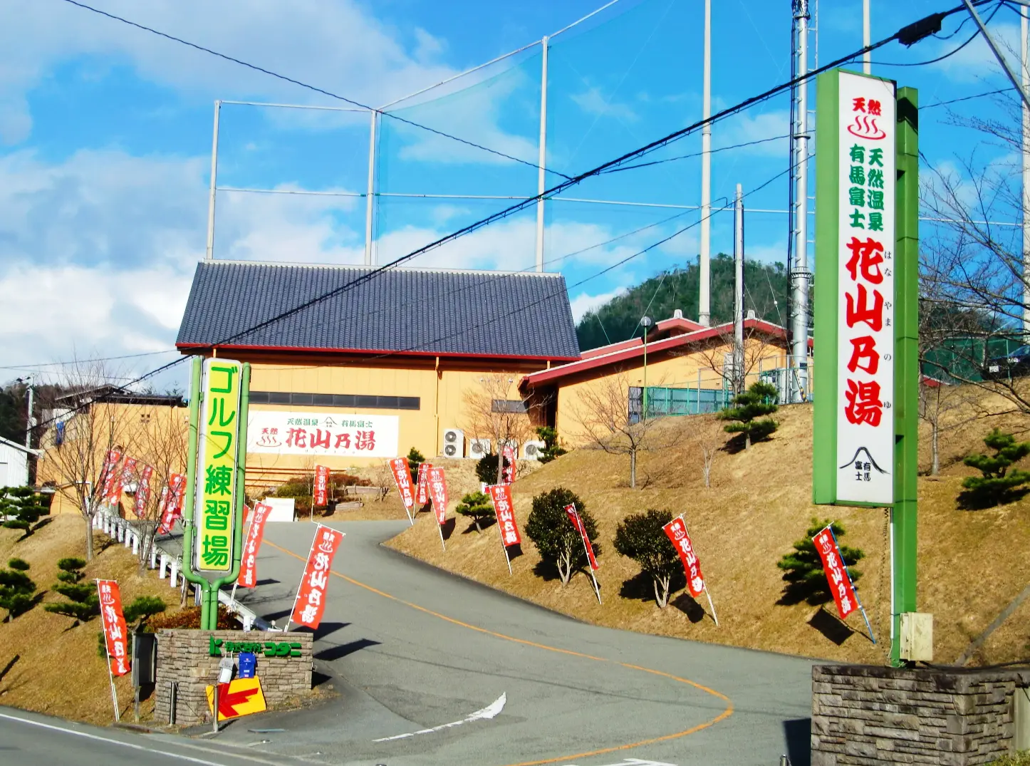 花山乃湯・三田スポーツクラブの看板と、道路から施設へ向かう進入路